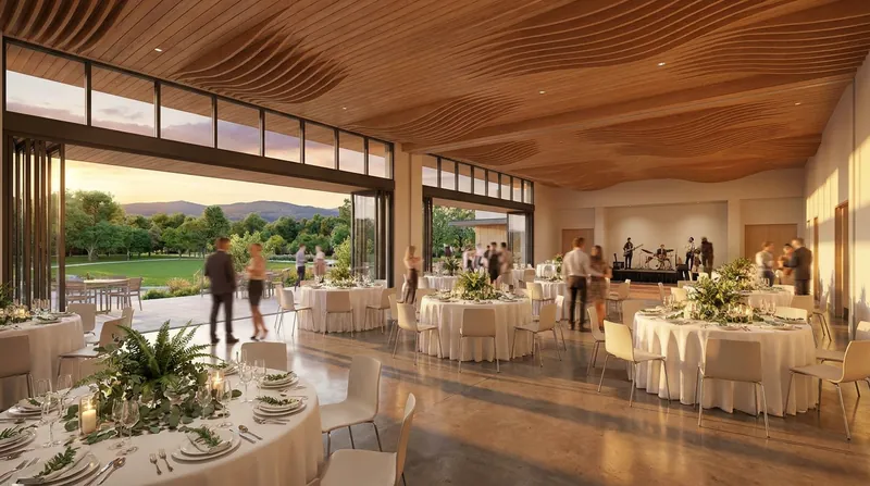 A wedding reception in a bright modern hall with a sculpted wood ceiling, round tables set in white and greenery, and glass doors open to a green park at golden hour