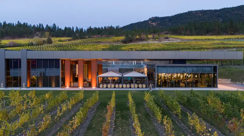 A winery lit up at dusk above the vines in Lake Country
